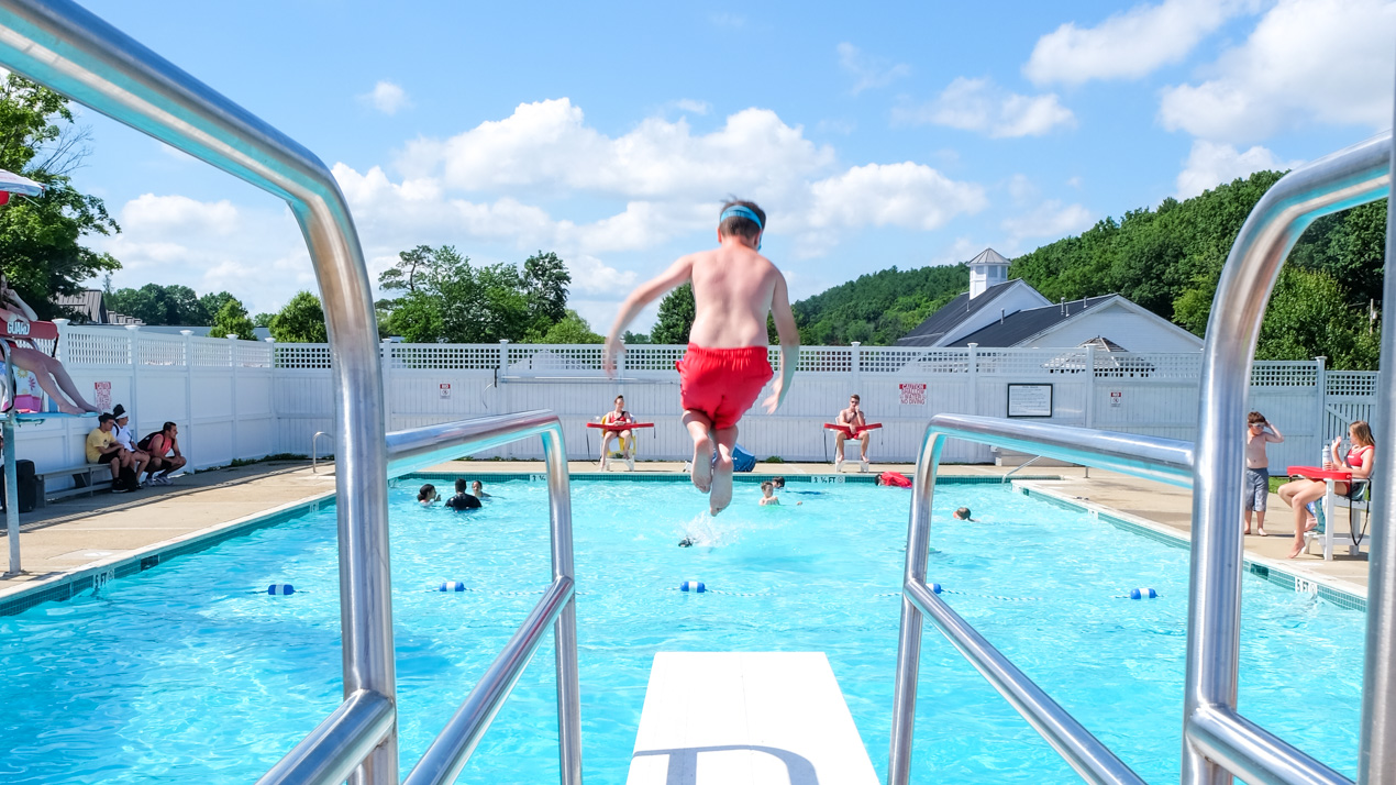 Boy jumping off of a diving board into the pool
